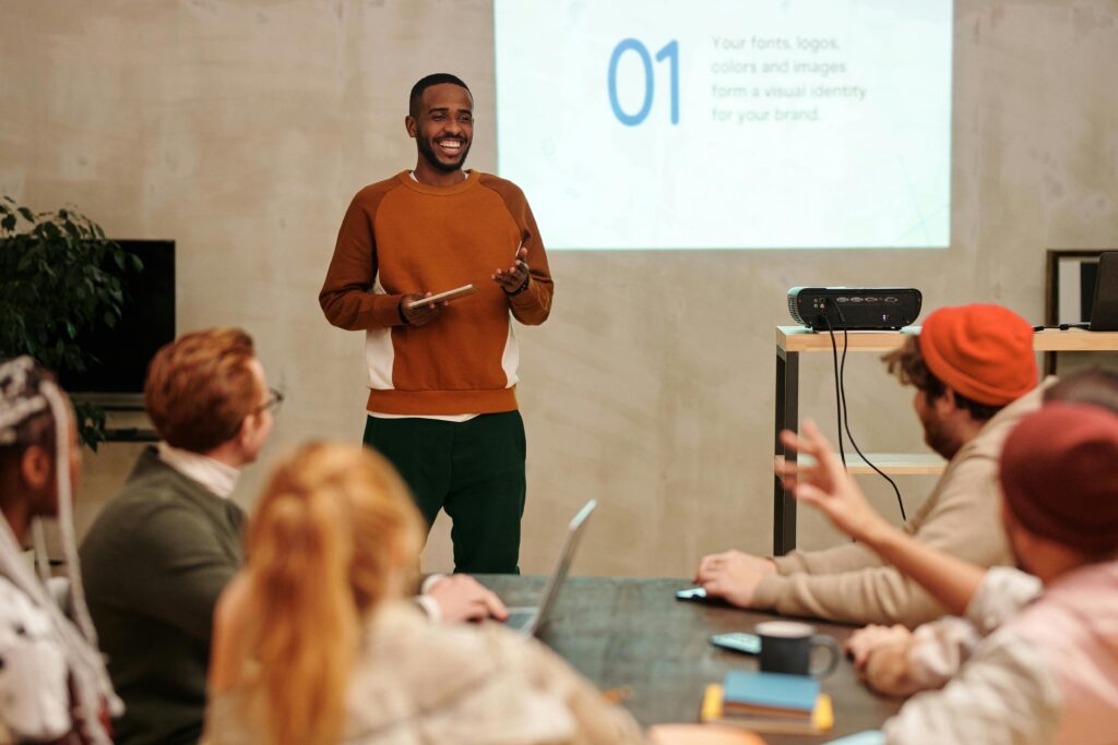 pexels-photo-6150527-6150527 A man delivers a presentation in a modern office to a diverse group of colleagues.
